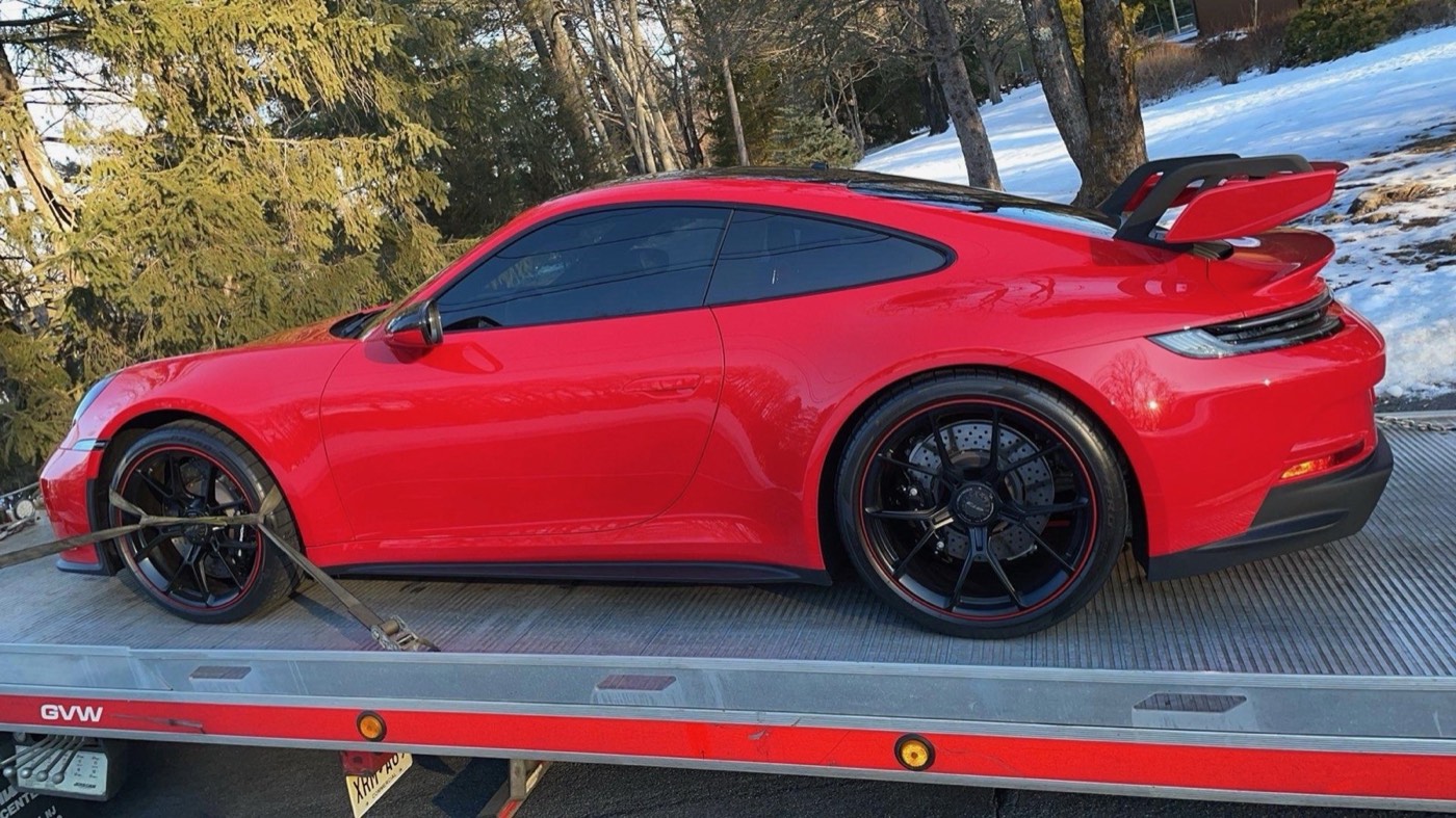 Porsche 911 rojo transportado por XXCELL Towing