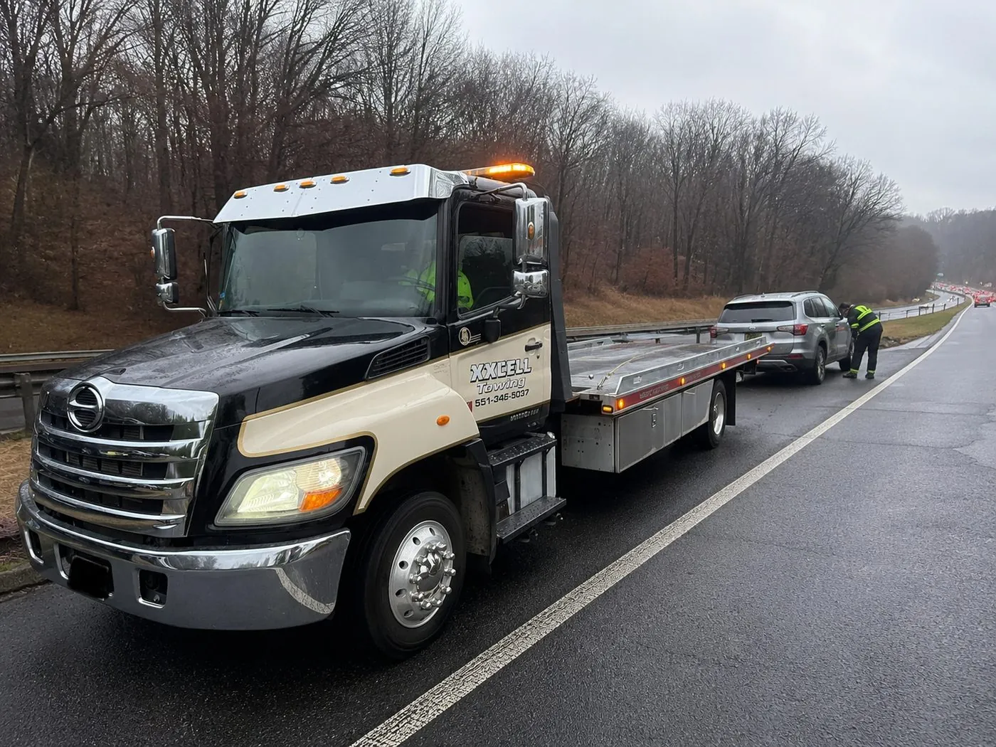 XXCELL Towing assisting a stranded vehicle on a rainy highway shoulder in Bergen County NJ